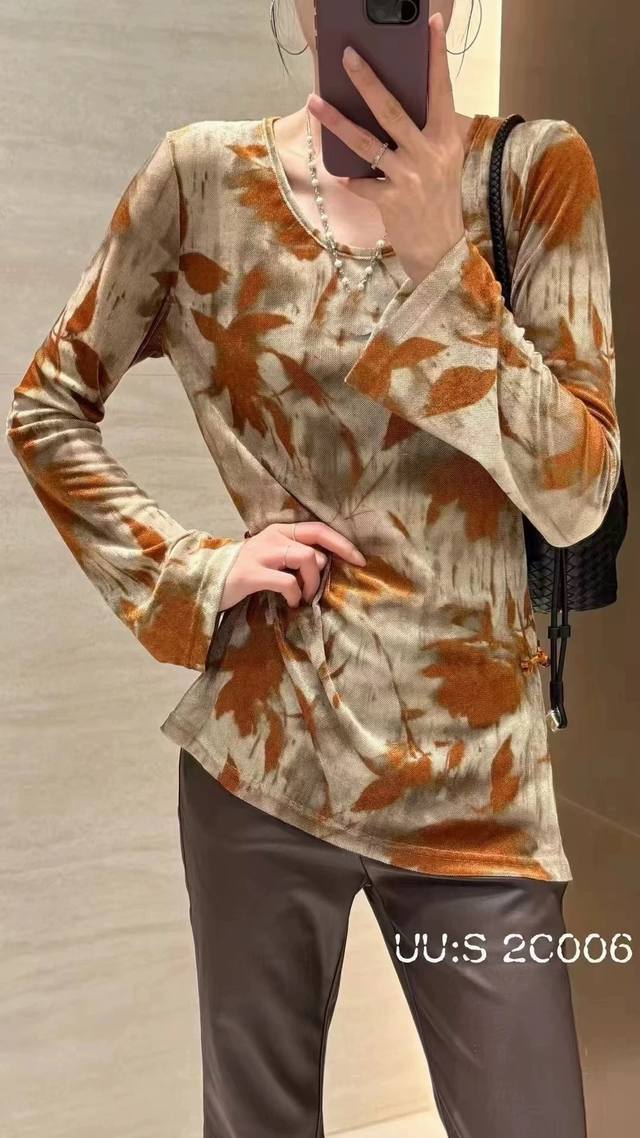 This buttoned elastic flocked blouse features a flocked print resembling autumn
